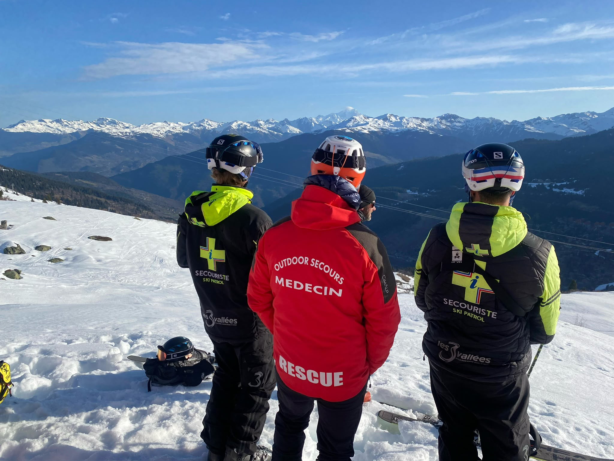 Médecin Outdoor Secours et secouristes sur une piste enneigée face aux montagnes